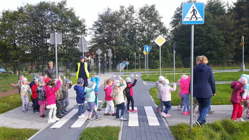 Dzielnicowi z przedszkolakami w miasteczku ruchu drogowego