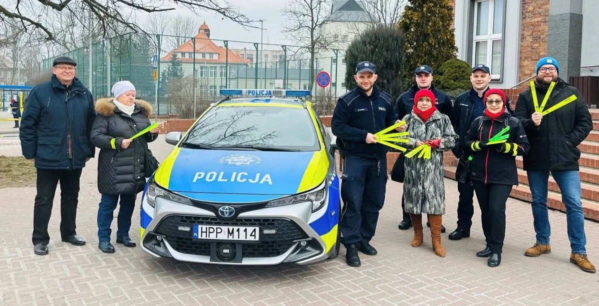 Policjanci wraz z seniorami rozdawali przechodniom odblaskowe opaski